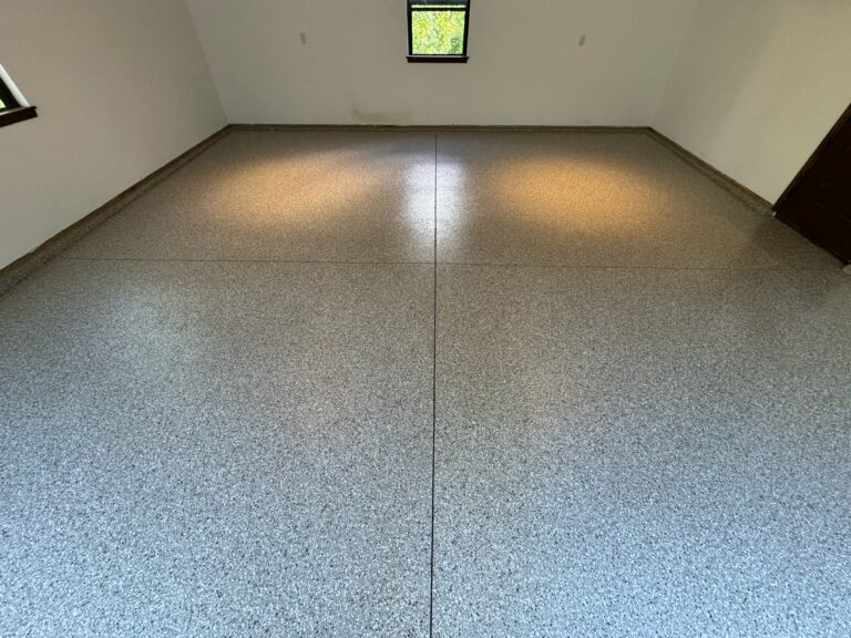 Close-up of freshly applied grey flake epoxy coating on residential garage floor, showing textured details and glossy finish.