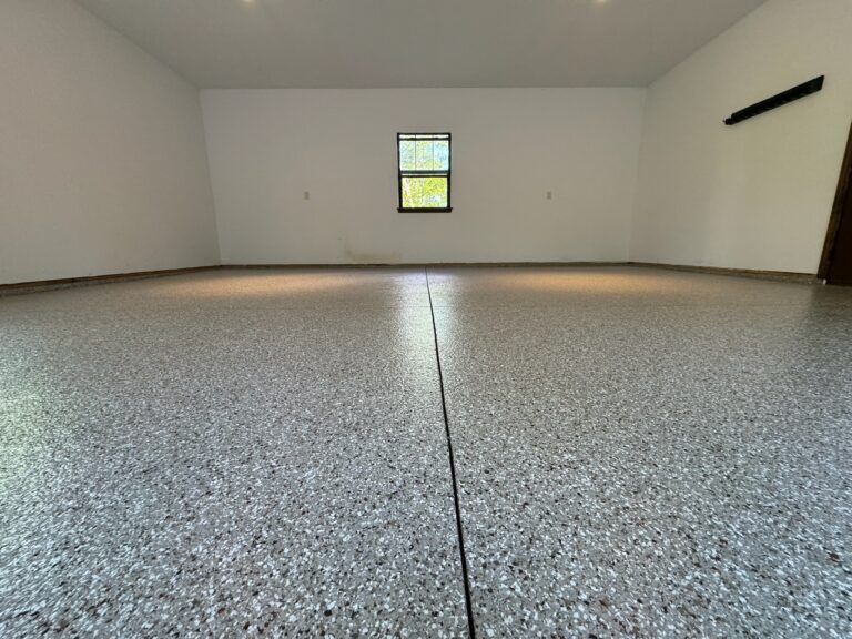 Overview of a finished flake epoxy garage floor with a subtle blend of black and silver flakes, emphasizing the floor's seamless and durable surface