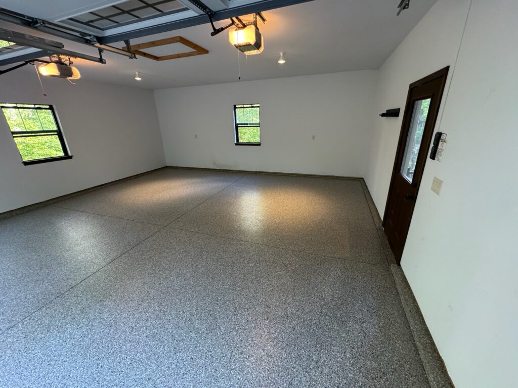 Wide-angle view of a completed flake flooring installation in a spacious garage, highlighting the uniform shine and robust texture