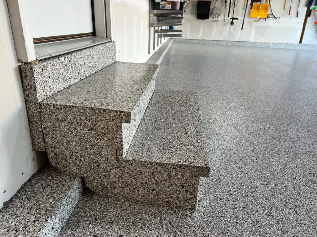 A close-up of epoxy-coated garage steps in O’Fallon, Missouri, showcasing a seamless application.